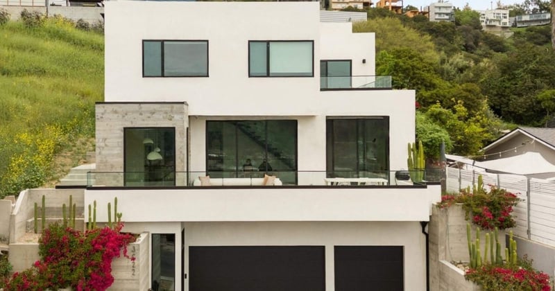 Modern multi-level home with white stucco, black-framed windows, and hillside landscaping in Greater Pasadena, CA.