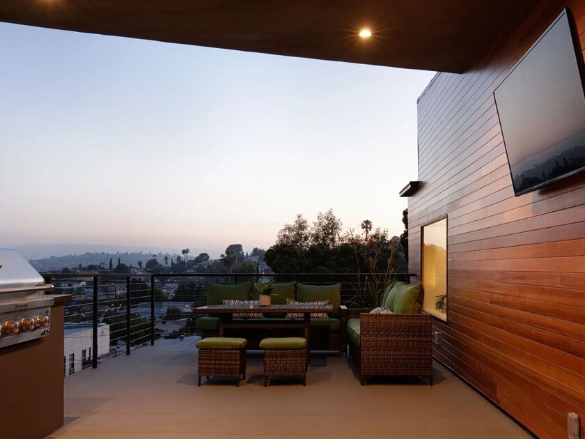 Covered outdoor living area with wicker seating, built-in grill, and hillside views in Altadena, CA.