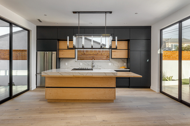 Black pendant lights illuminating a modern wood and white kitchen