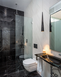 Textured stone, glass, wood, and tile meeting in a modern bathroom