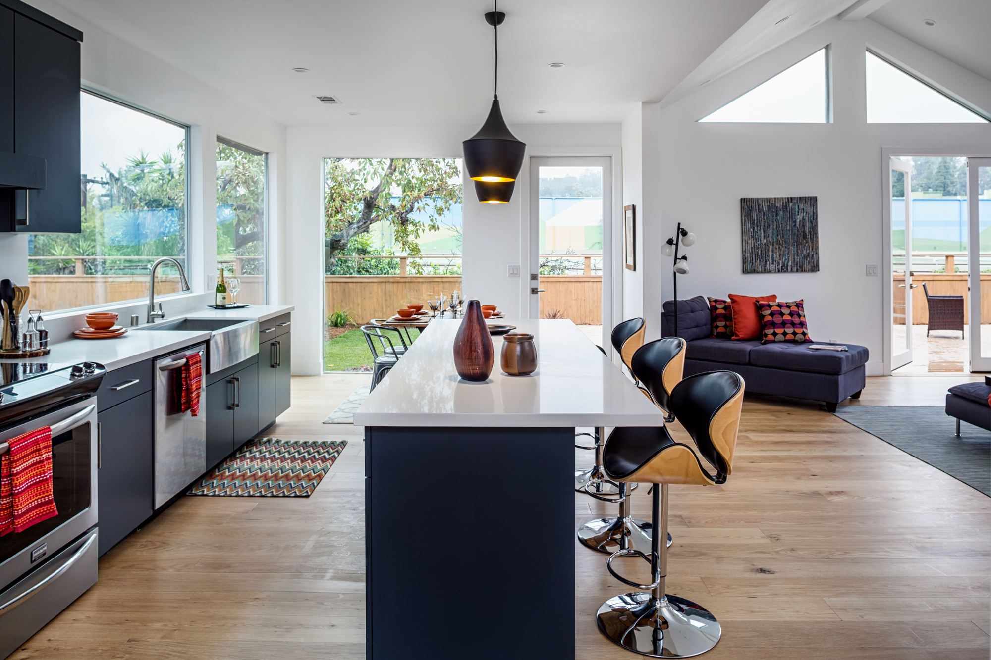 Open-concept kitchen and living area with a large island, vaulted ceilings, and expansive windows overlooking the backyard.
