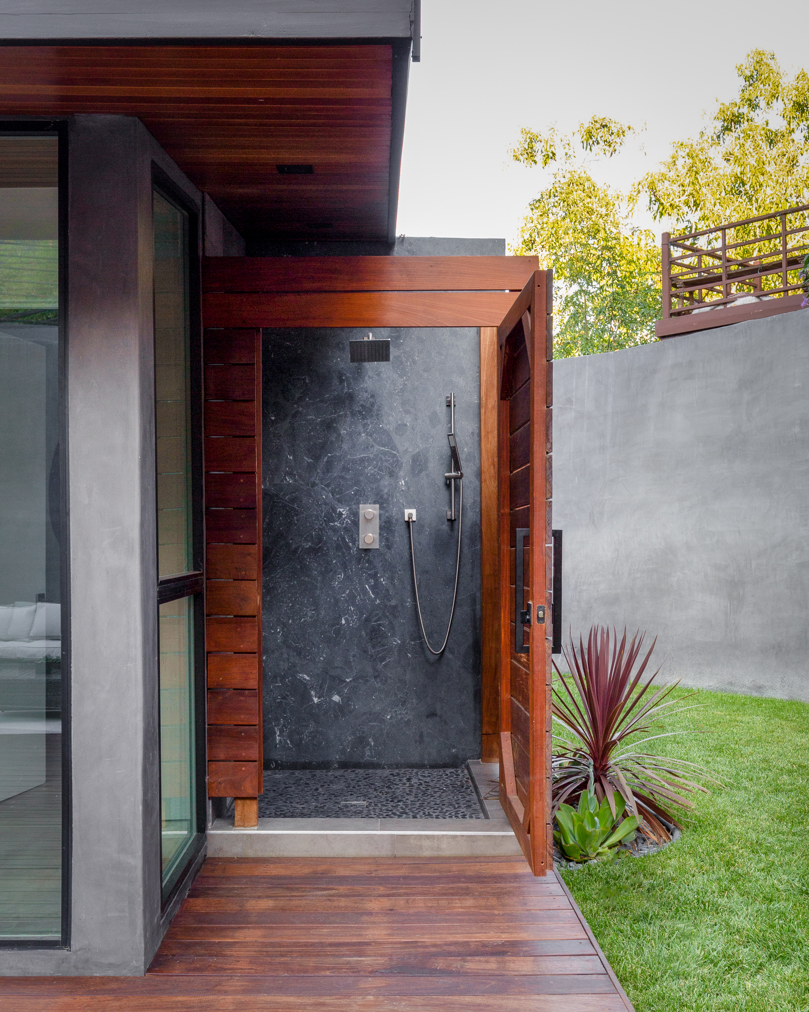 Private outdoor shower with dark stone tile, wood privacy screening, and direct access beside the home’s landscaped yard. Private outdoor shower with dark stone tile, wood privacy screening, and direct access beside the home’s landscaped yard.
