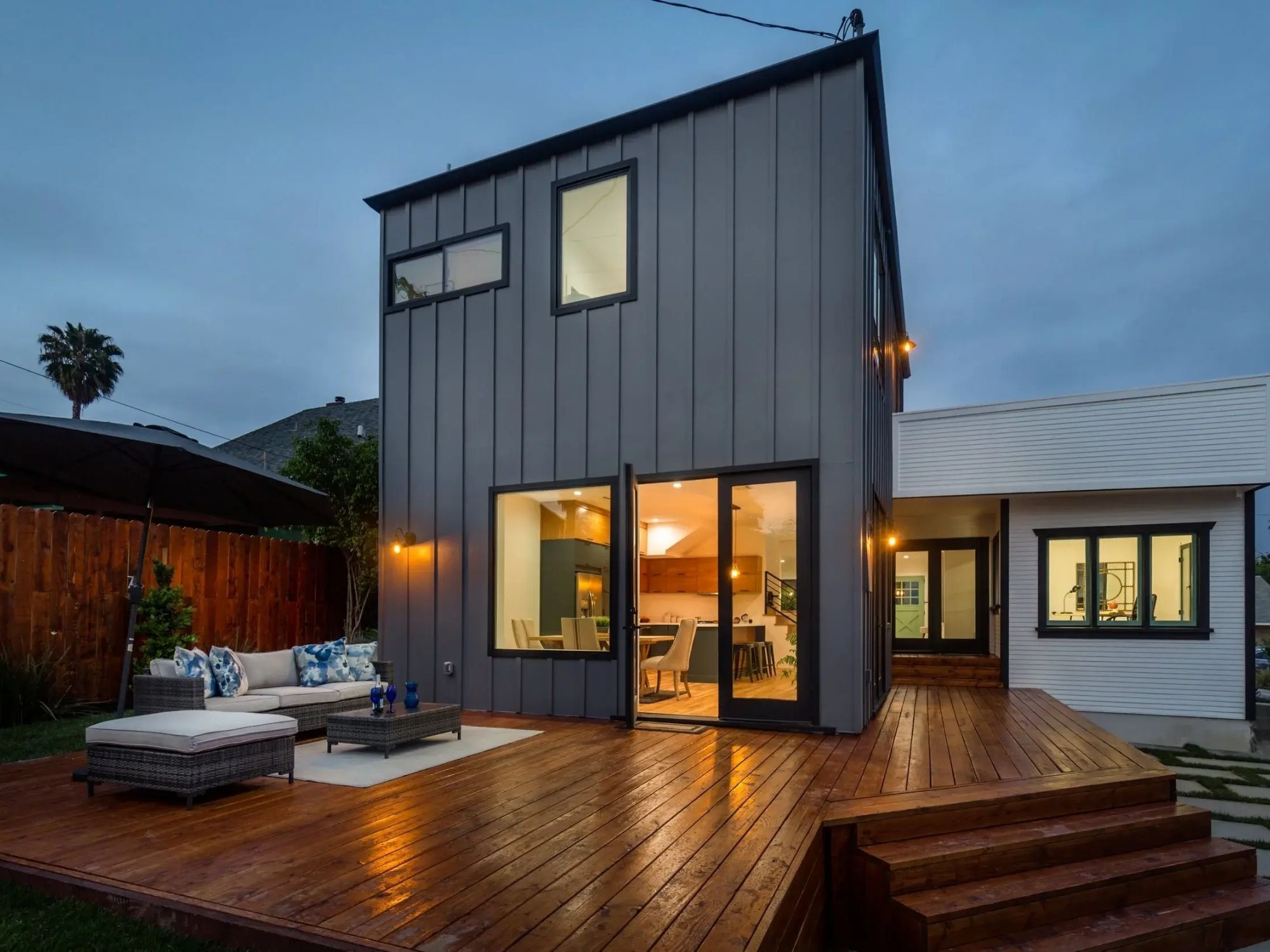 Modern two-story home with dark metal siding, large windows, and a spacious wood deck in Altadena, CA